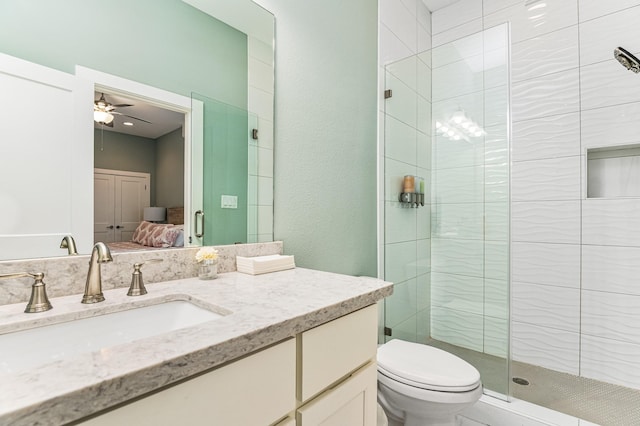 bathroom with ceiling fan, vanity, an enclosed shower, and toilet