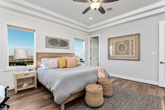 bedroom featuring wooden walls, ceiling fan, and dark wood-type flooring