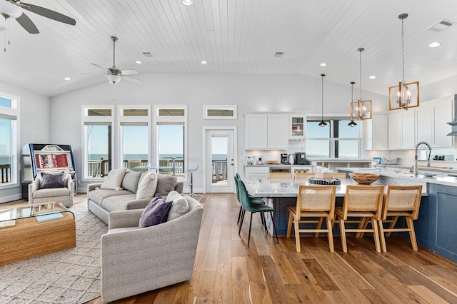 living room featuring ceiling fan with notable chandelier, light hardwood / wood-style floors, a water view, and wood ceiling