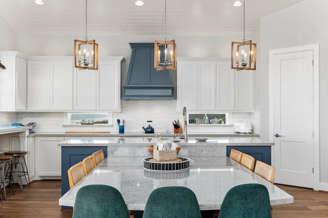 kitchen with decorative light fixtures, dark hardwood / wood-style floors, white cabinetry, and premium range hood