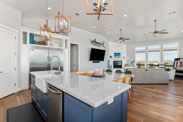 kitchen featuring blue cabinetry, lofted ceiling, light hardwood / wood-style floors, and decorative light fixtures