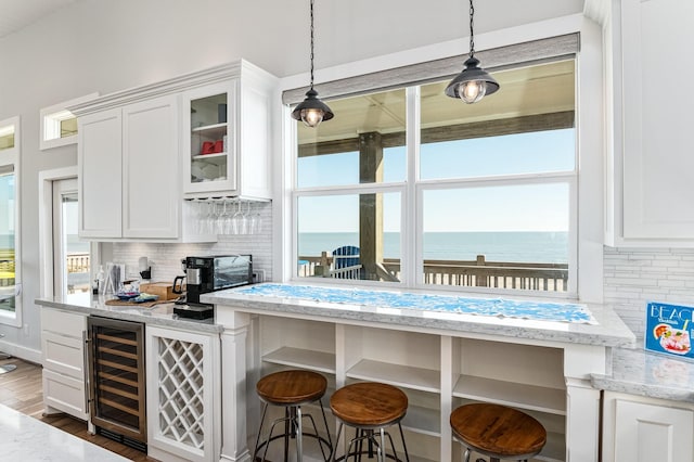 kitchen with dark hardwood / wood-style floors, a water view, white cabinetry, and beverage cooler