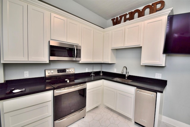 kitchen featuring sink, white cabinetry, stainless steel appliances, and light tile patterned floors