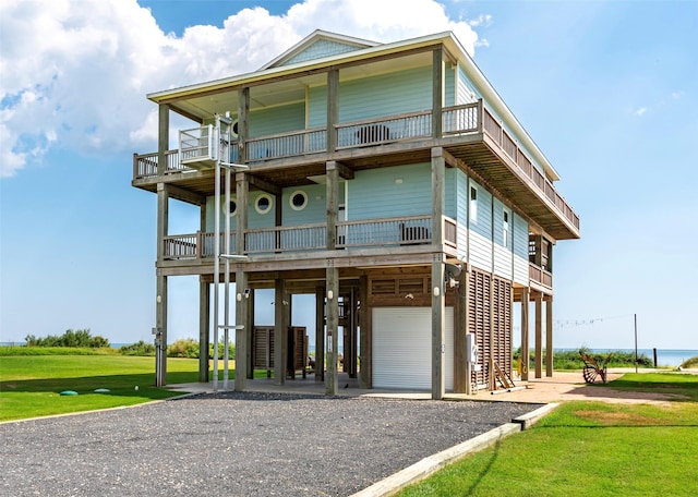 beach home featuring a carport, a balcony, and a front yard