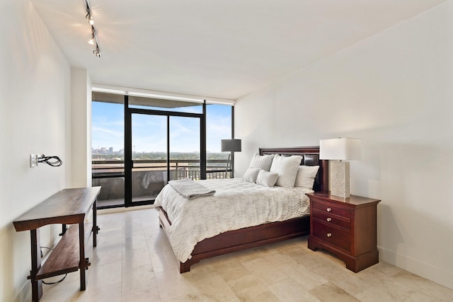 bedroom featuring access to exterior, rail lighting, and floor to ceiling windows