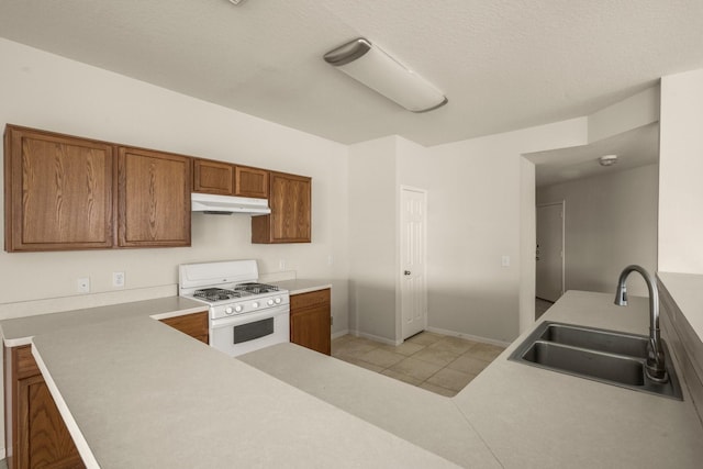 kitchen with sink, light tile patterned floors, a textured ceiling, white gas stove, and kitchen peninsula