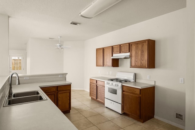 kitchen with sink, ceiling fan, white gas range, a textured ceiling, and light tile patterned floors