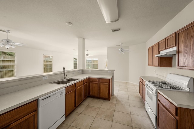 kitchen featuring kitchen peninsula, white appliances, a textured ceiling, sink, and light tile patterned floors