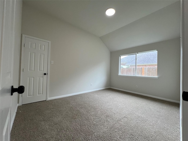 unfurnished room featuring vaulted ceiling and dark colored carpet