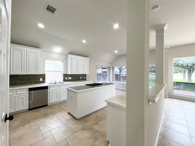 kitchen with a center island, tasteful backsplash, vaulted ceiling, white cabinets, and appliances with stainless steel finishes