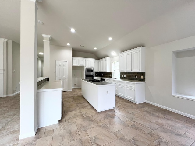 kitchen featuring a center island, stainless steel microwave, lofted ceiling, tasteful backsplash, and white cabinetry