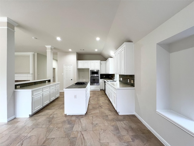 kitchen with a center island, tasteful backsplash, lofted ceiling, white cabinets, and appliances with stainless steel finishes