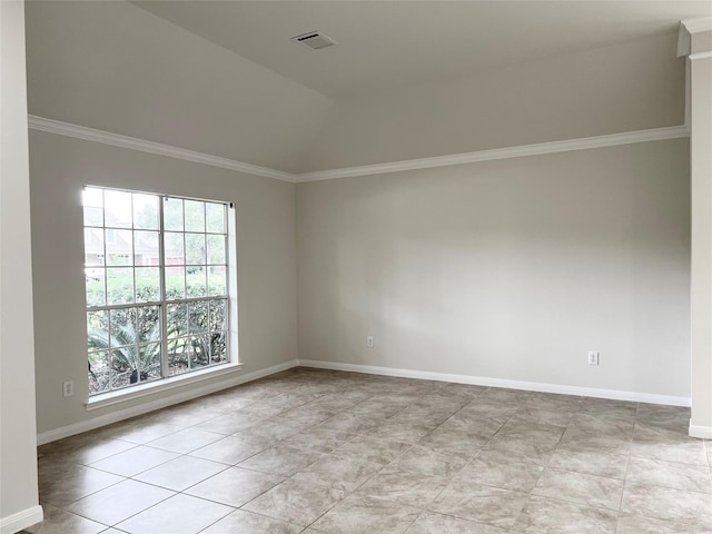 empty room with light tile patterned floors, vaulted ceiling, a wealth of natural light, and ornamental molding