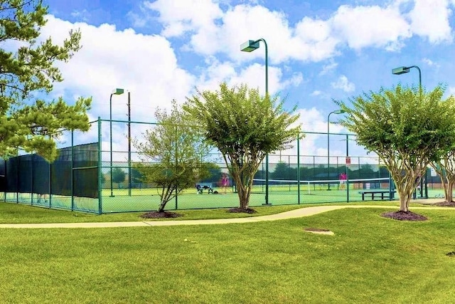 view of property's community with a lawn and tennis court