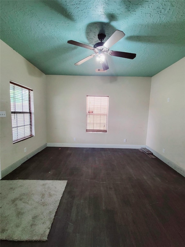 empty room with a textured ceiling, ceiling fan, and dark hardwood / wood-style floors