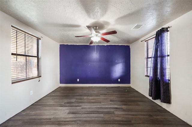 spare room featuring a textured ceiling, ceiling fan, and dark wood-type flooring