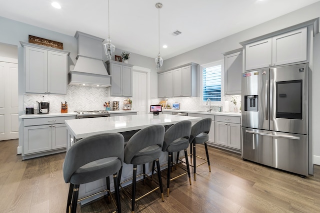 kitchen featuring hardwood / wood-style floors, sink, hanging light fixtures, appliances with stainless steel finishes, and a kitchen island