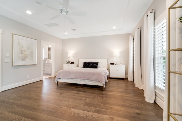 bedroom featuring ceiling fan, dark hardwood / wood-style flooring, ensuite bathroom, and multiple windows