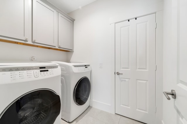 clothes washing area featuring cabinets, light tile patterned floors, and washing machine and dryer