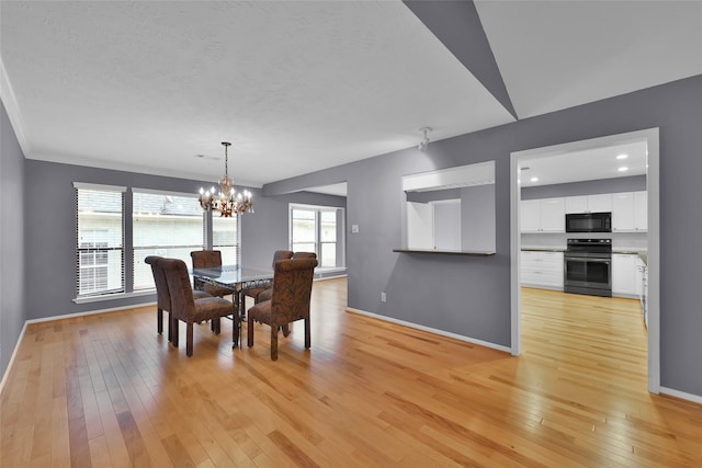 dining area with ornamental molding, light hardwood / wood-style floors, and an inviting chandelier