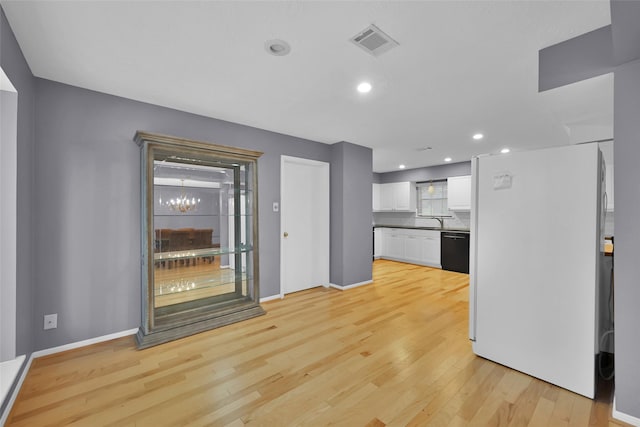 kitchen with dishwasher, light wood-type flooring, white fridge, and white cabinetry