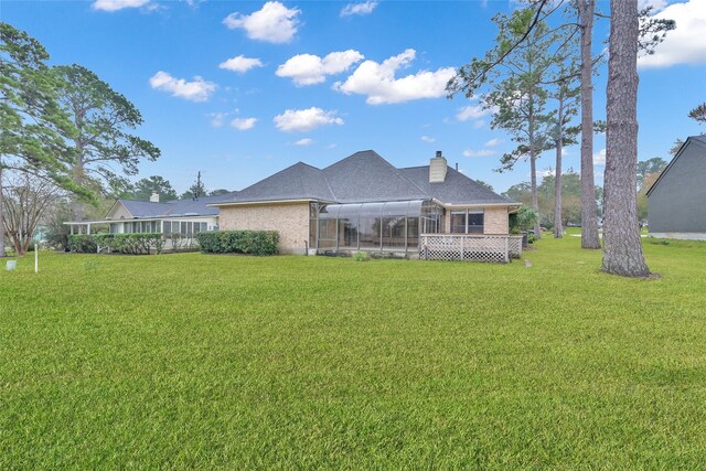 rear view of property with a lanai and a lawn