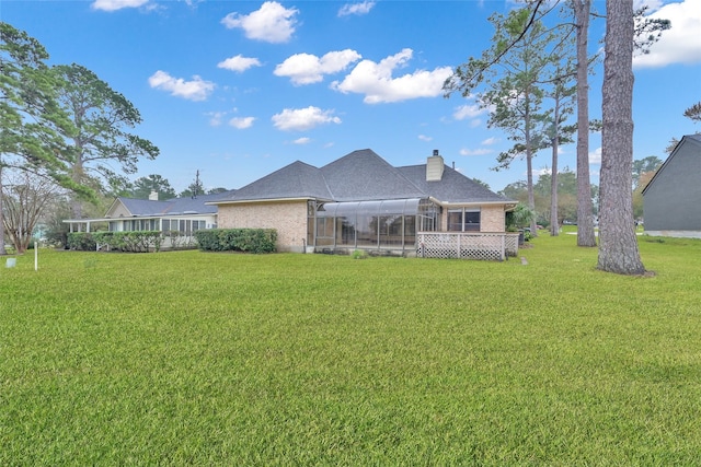 rear view of house with a yard and a lanai