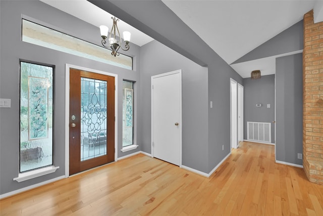 foyer entrance with light hardwood / wood-style floors, vaulted ceiling, and a notable chandelier