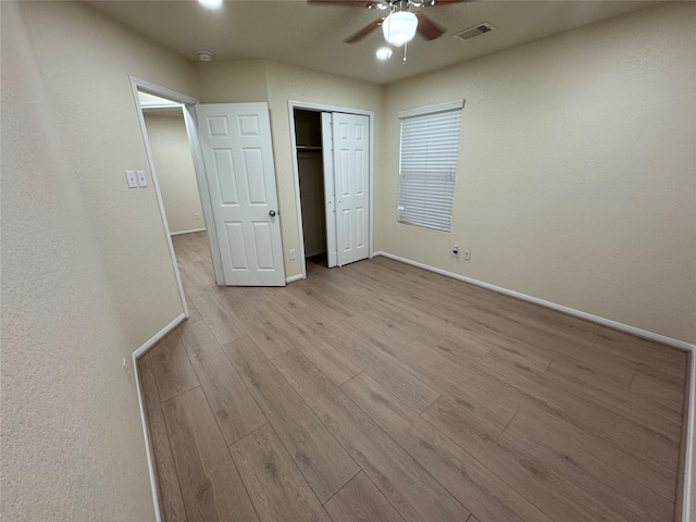 unfurnished bedroom with light wood-type flooring, a closet, and ceiling fan