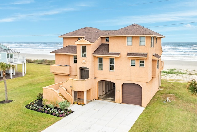 view of front facade with a beach view, a water view, a garage, and a front yard