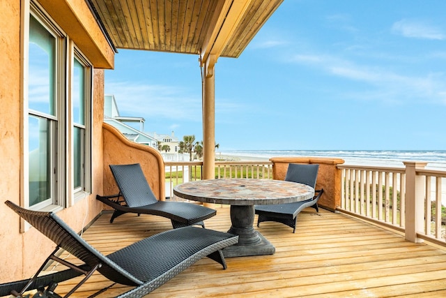 wooden terrace featuring a water view and a view of the beach