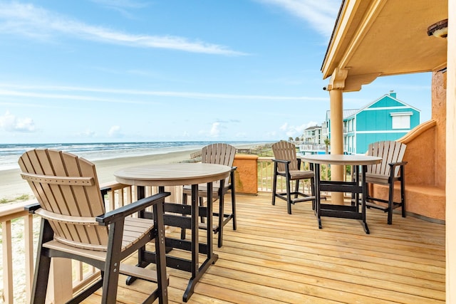 wooden deck featuring a water view and a beach view