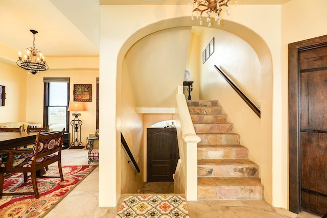 stairs featuring a chandelier