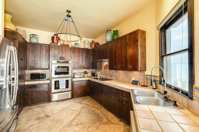 kitchen with pendant lighting, a healthy amount of sunlight, appliances with stainless steel finishes, and tile countertops