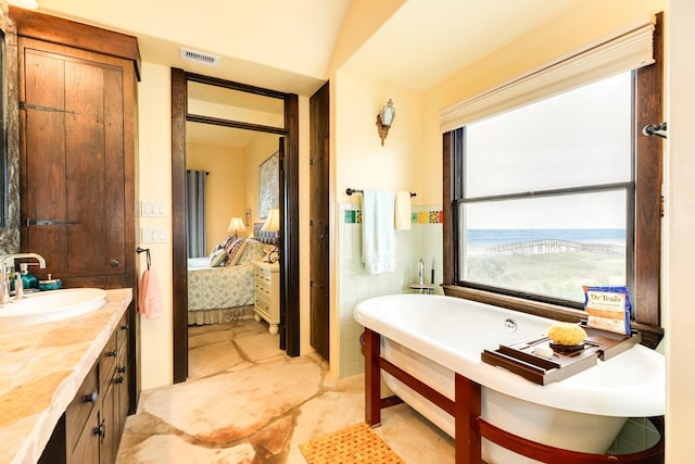 bathroom with vanity, a bathtub, and tile walls