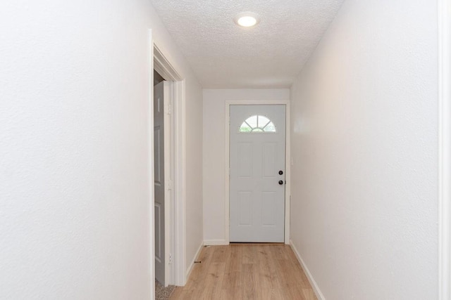 entryway with a textured ceiling and light wood-type flooring