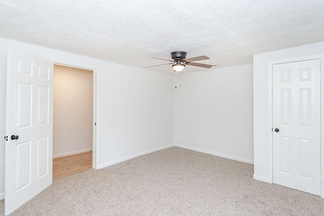 unfurnished room featuring a textured ceiling, ceiling fan, and light carpet