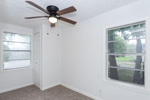 carpeted spare room with a textured ceiling and ceiling fan