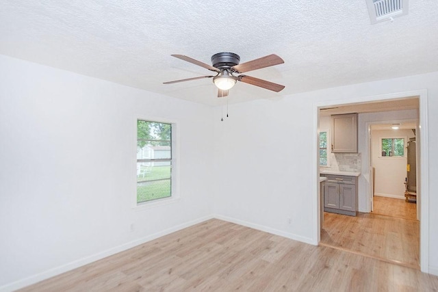 empty room featuring a textured ceiling, ceiling fan, and light hardwood / wood-style flooring