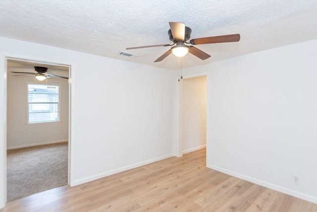 spare room featuring a textured ceiling, ceiling fan, and light hardwood / wood-style flooring