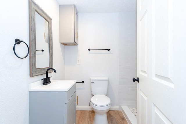 bathroom with walk in shower, hardwood / wood-style flooring, vanity, and toilet