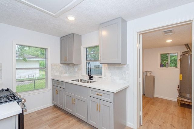 kitchen featuring stainless steel stove, gray cabinets, tasteful backsplash, and sink