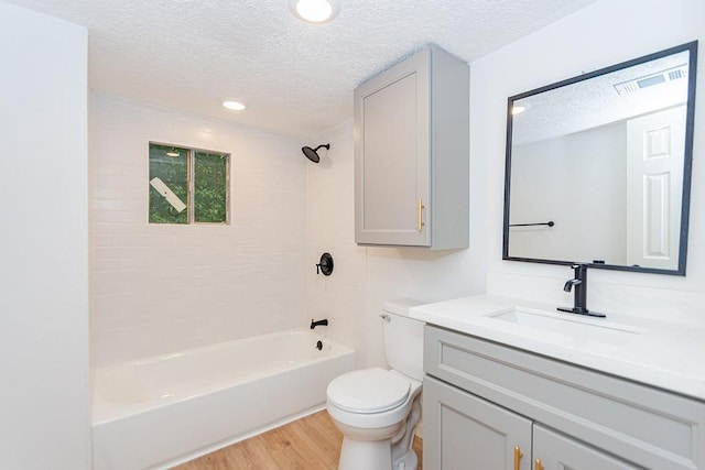 full bathroom with toilet, a textured ceiling,  shower combination, wood-type flooring, and vanity