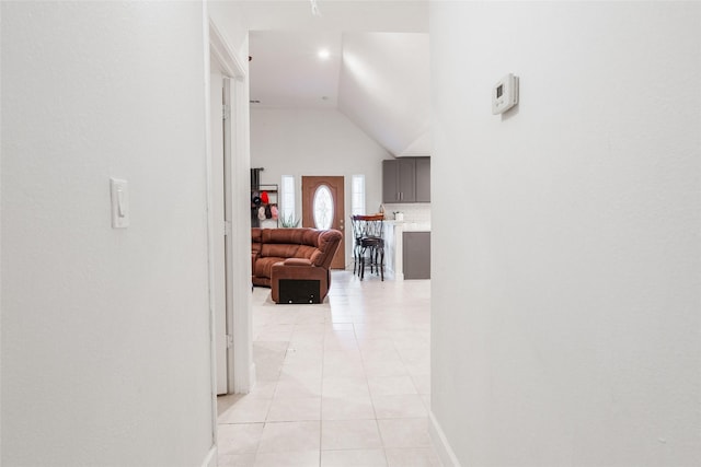 corridor featuring light tile patterned floors and high vaulted ceiling