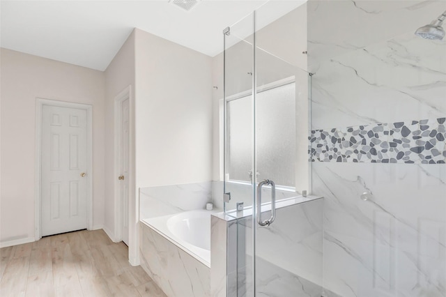 bathroom with hardwood / wood-style flooring and independent shower and bath