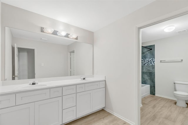 full bathroom with vanity, tiled shower / bath combo, hardwood / wood-style flooring, and toilet