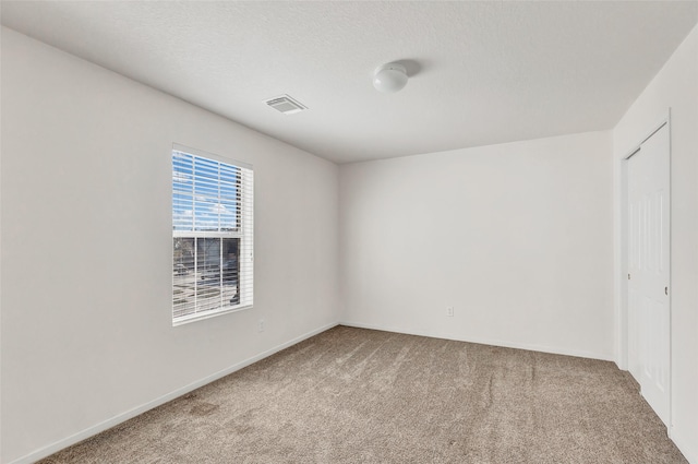 empty room with carpet flooring and a textured ceiling