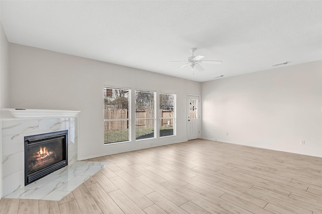 unfurnished living room featuring ceiling fan, a high end fireplace, and light hardwood / wood-style floors