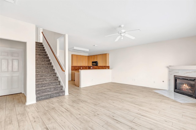 unfurnished living room with a fireplace, light hardwood / wood-style floors, and ceiling fan