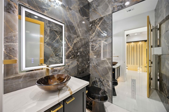 bathroom with vanity, toilet, and tile walls